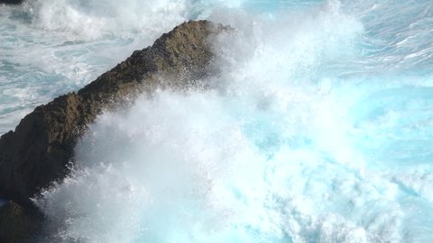 SLOW MOTION CLOSE UP: Huge turbulent foamy ocean wave breaking. Perfect barrel wave rolling upon the shore splashing. Big powerful swell wave crushing over the sharp rocky reef spraying sea waterdrops