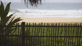 Simple fence separates a private bungalow compound from the tropical beach with rolling breakers. just a few steps away. UltraHD 4k video