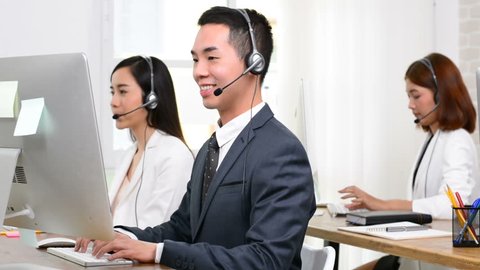 Asian telemarketing service agent team talking on the phone to customers with a friendly and helpful attitude in call center office