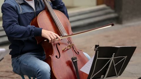 A group of musicians playing cellos on a street in a European city Video de stock