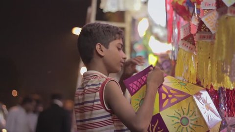 A young kid making a paper lantern on a roadside stall during Diwali or Deepawali festival in India
