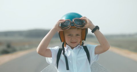 CU Little boy putting on vintage googles and helmet, pretending to be a pilot. 4K UHD RAW edited footage