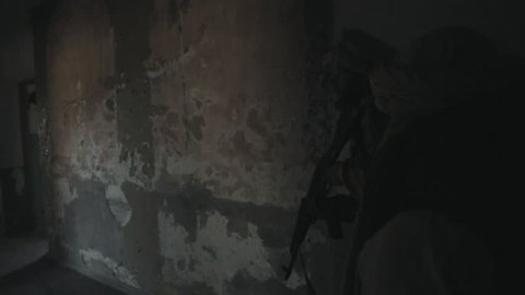 Two armed Mujahideen walk along the corridors of the abandoned building and hunt down the enemy