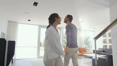 Happy Young Couple Enters Their Newly Purchased Home, They're Full of Wonderment. House is Bright, Has Floor to Ceiling Windows and Seaside View. Shot on RED EPIC-W 8K Helium Cinema Camera.