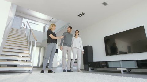 Professional Real Estate Agent Shows Stylish Modern House to a Beautiful Young Couple. Shot on RED EPIC-W 8K Helium Cinema Camera.