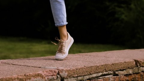 Close-up shot of feet of modern female dancer dancing on a top of brick wall in the street. 4K