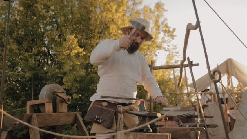 Medieval blacksmith works with metal