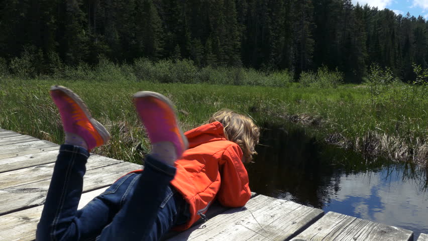 Girl Leaning Over a Wooden Pier at a Cottage