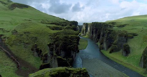 Aerial tracking view of green grassy canyon in Iceland