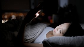 Woman looking at smart phone and lying on bed