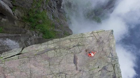 Aerial shot magnificent landmark in Norway, Europe. Tourists walk on large rock. Preikestolen Landscape, Prekestolen, Preacher's Pulpit or Pulpit Rock. Amazing scenery, mountains, steep cliffs in fog