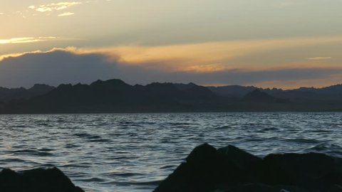 A picturesque sunset - the calm waves of the lake and the mountains in the distance.
