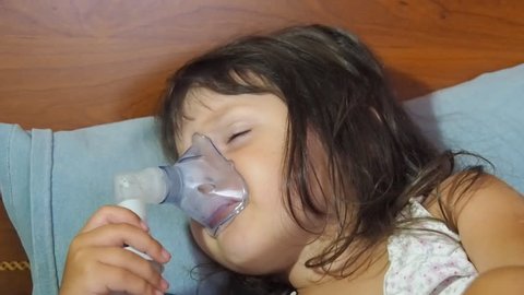 The child has asthma. A little girl with a nebulizer makes inhalation.