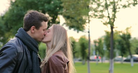 young beautiful couple hugging and kissing in the park