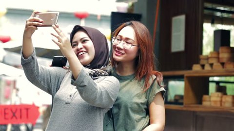 Portrait of beautiful muslim and asian woman smiling on camera and taking selfies  with three kind of tones (cyan - orange, contrast, and raw)