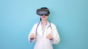 beautiful pretty hospital doctor woman wearing VR technology standing in blue background and viewing 3D simulation video doing surgery work.