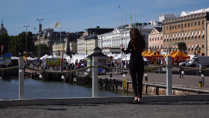 Young woman in black come and stay at Helsinki port embankment, market square on background. Tourist lady admire beautiful city at warm sunny autumn day. Many tents and stalls at weekend bazaar | Shutterstock HD Video #30744700