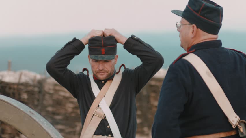 French soldier corrects the cap while the other shoots the gun