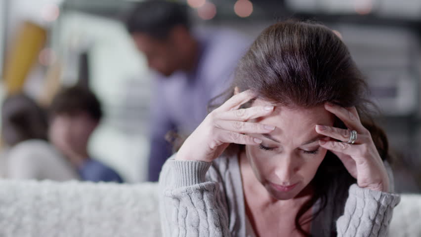 An attractive caucasian woman is upset and stressed about events in her life which are beyond her control. Her husband and children are unaware of her anxiety. In slow motion. Royalty-Free Stock Footage #3075025