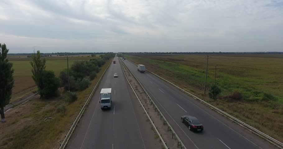 Aerial view above flat highway to the horizon among agricultural fields