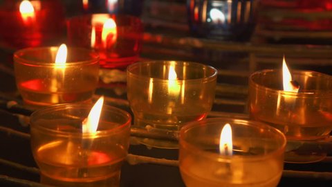Candles burning in catholic church. Festive glow in european cathedral. Holy place illuminated by bright flames from many fiery candles
