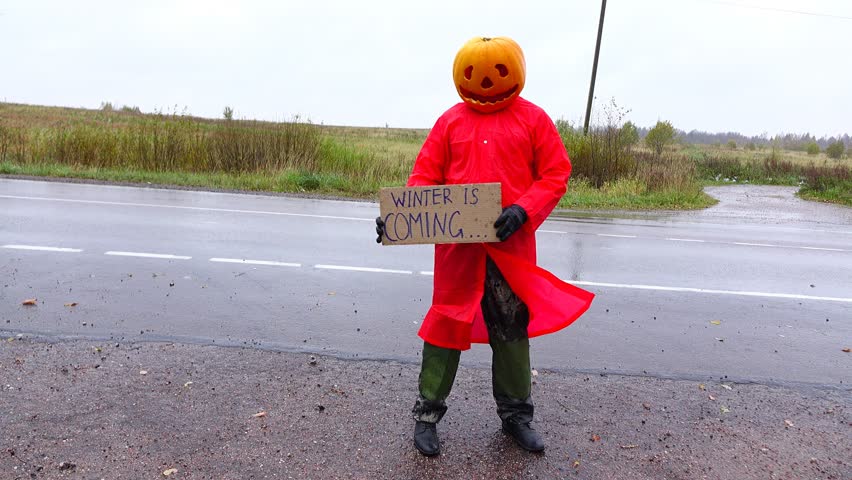 Pumpkinhead Jack in red raincoat stay back to road with warning sign 