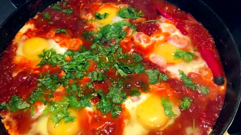 Shakshouka or shakshuka is a North African Jewish origin dish of eggs poached in a sauce of tomatoes, chili peppers, and onions, often spiced with cumin.