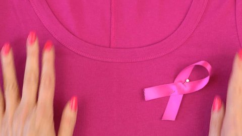 Pink Ribbon charity for Breast Cancer Awareness month in October, pinning pink ribbon to a pink tee shirt.