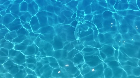 Pure blue water in pool with light reflections. Slow motion.