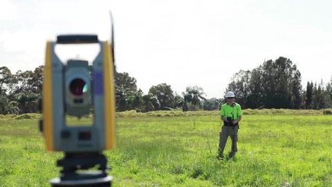 Land Surveyor Takes Measurements In A Field Using A Robotic Theodolite