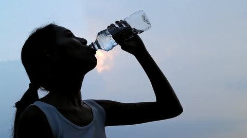 Slow motion of woman drinking water in sunset time 