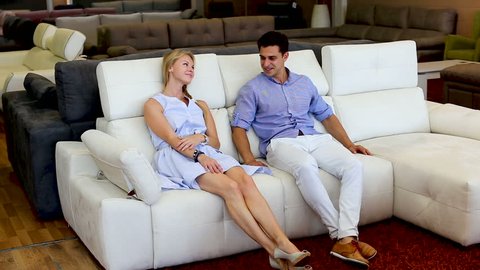 Happy couple are choosing new sofa in furniture store