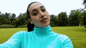 Young attractive woman making selfie on the smart phone during the running in the green park. 4k UHD video. Morning jogging. Smile good self condition concept.
