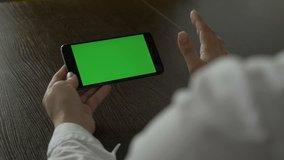 Woman holding a mobile phone with a green screen. For your video content.