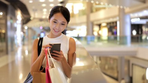 Woman using mobile phone and shopping bags 