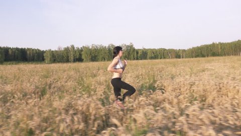 Young pretty girl jogging outdoors in fields and forests