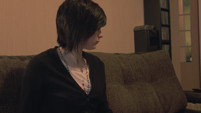 Pretty girl sits upset or bored on sofa then leans back