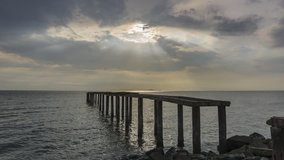 Dramatic cloud with ray over the abandoned old jetty.