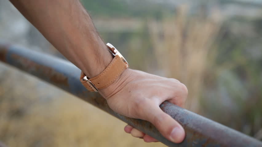 Hand of a man is grabbing the metallic tube of a balcony