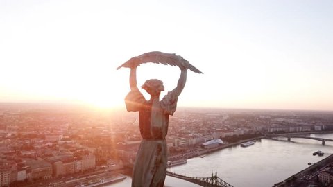 Aerial footage of Budapest, Hungary, at  Sunrise with intense flare, by the liberty statue and view of the early sun over the city.