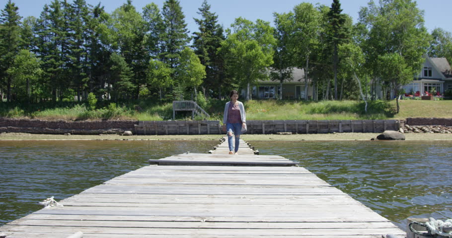 Woman walking on dock towards camera - slow motion