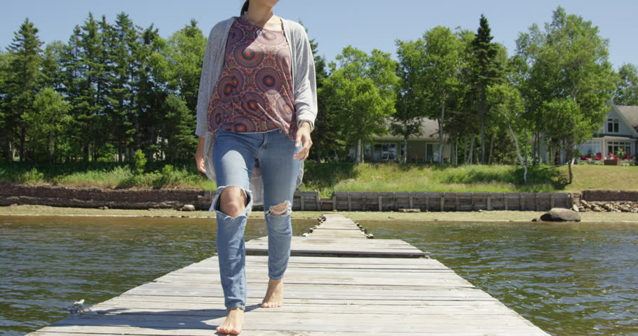 Woman walking on dock with torn jeans - close up on legs