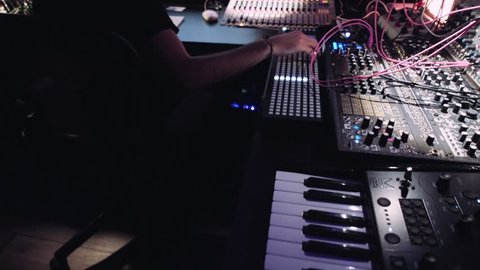 Camera moves above many sound production panels in professional studio with musician workind on sound check and mixing and recordings new mixtape