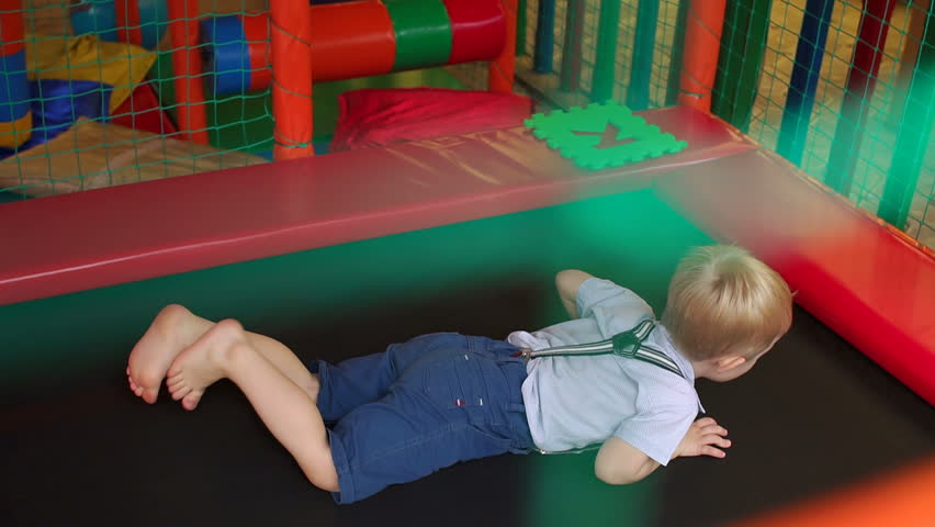 Little boy in shirt and shorts with suspenders, jumping on the trampoline with the children