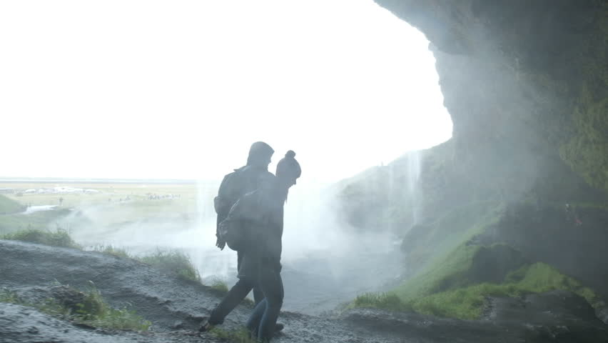 couple standing on hill at waterfall. Silhouette of a couple holds hands