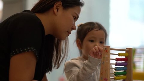 mother teaching daughter to count number with toy