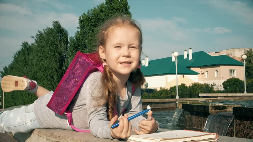 Beautiful girl draws in a notebook near the fountainn 4k