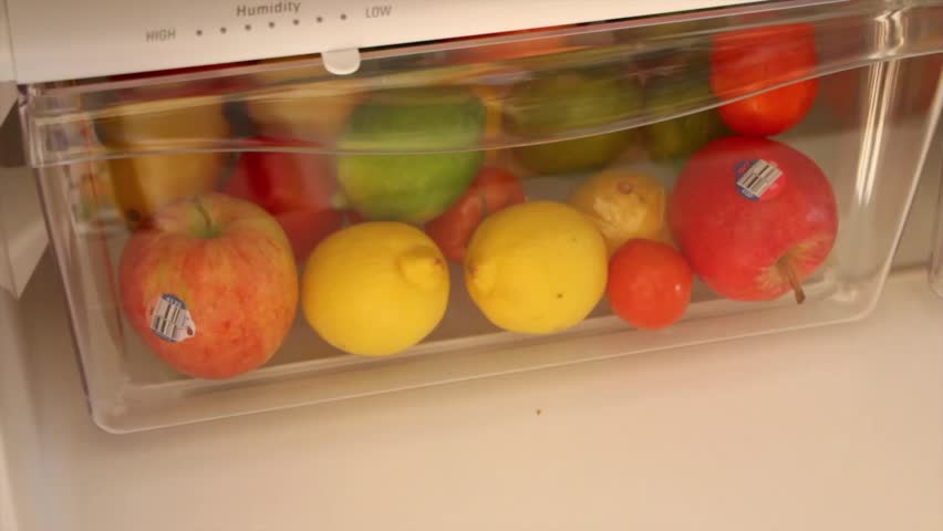 Man looks through fruit drawer in fridge