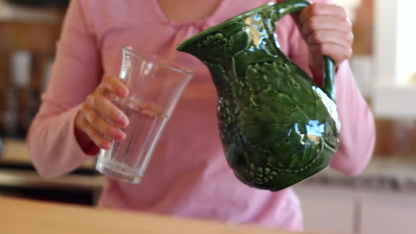 A woman pours a glass of orange juice