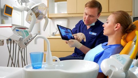 In the dentist office the dentist shows the patient an x-ray image on the tablet